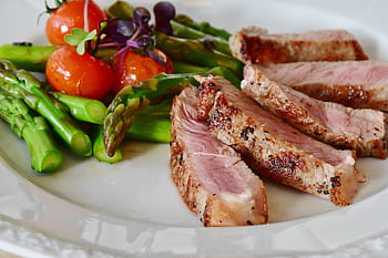 Close-up of grilled steak slices with asparagus and cherry tomatoes, perfect for a healthy meal. HD wallpaper