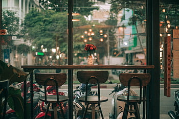 A cozy café in Ho Chi Minh City featuring a view of bustling streets with scooters. HD wallpaper