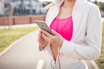 Young woman outdoors using smart and ears for workout music. HD wallpaper