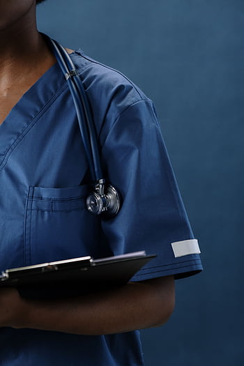 Close-up of a healthcare professional in blue scrubs with a stethoscope and clipboard. HD phone wallpaper