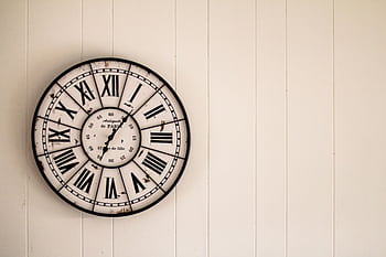 Retro wall clock with Roman numerals on a white wooden background. HD wallpaper