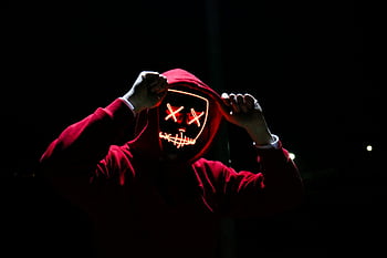 A spooky illuminated mask figure with a red hoodie in a dark setting, perfect for Halloween themes. HD wallpaper