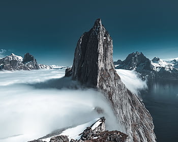 A stunning, snow-capped mountain peak rising above the clouds, creating an epic natural landscape. HD wallpaper