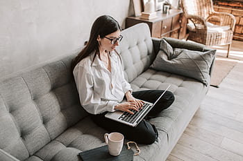Woman in a cozy home setting working on a laptop for remote work and relaxation. HD wallpaper
