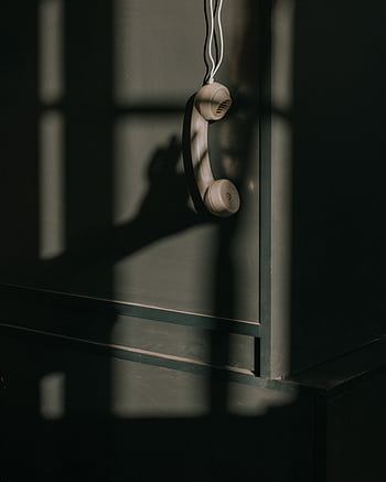 A vintage tele handset hangs against a wall with dramatic lighting and shadows. HD phone wallpaper