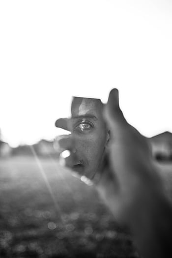 Creative black and white portrait featuring a man's reflection in a broken mirror piece, held by a hand. HD phone wallpaper