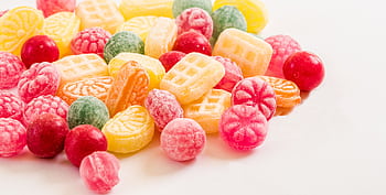 A vibrant display of assorted colorful hard candies on a white background. HD wallpaper