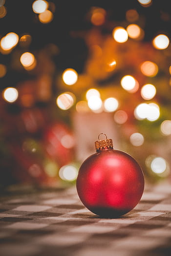 Vibrant red Christmas ornament with bokeh background, perfect for holiday promotions. HD phone wallpaper