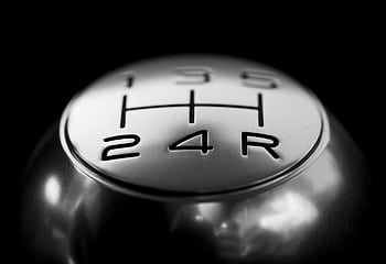 Detailed close-up of a stainless steel gear shift knob against a black background. HD wallpaper