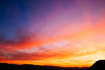 Beautiful colorful sunset sky with vibrant hues over mountain silhouettes. HD wallpaper