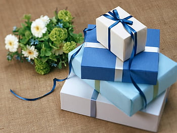 Three beautifully wrapped gift boxes with blue ribbons arranged beside a floral bouquet. HD wallpaper
