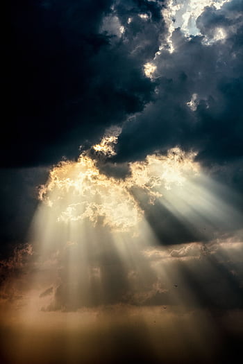 Sun rays piercing through dark clouds create a dramatic sky scene. HD phone wallpaper