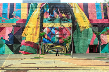 Colorful mural depicting a native face on an urban street wall with a passerby. HD wallpaper