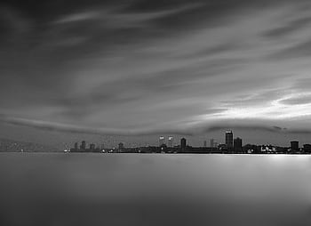 Elegant black and white cityscape with a dramatic skyline and blurred water. HD wallpaper