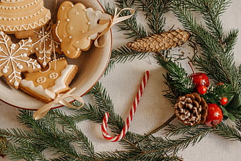 Cozy Christmas scene with cookies, pine branches, and candy cane on a table. HD wallpaper