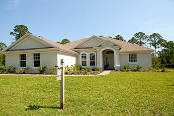 Beautiful suburban house with lush lawn, showcasing a for sale sign under a clear blue sky. HD wallpaper