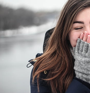 A woman enjoys the cold weather with a joyful smile, dressed warmly in winter clothing. HD phone wallpaper