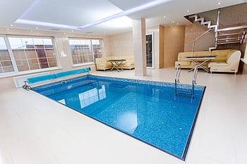 Luxurious indoor pool area featuring modern design and elegant furnishings. HD wallpaper