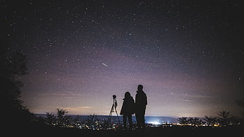 A couple stargazes under a starry sky in Elkton, VA, capturing the beautiful Milky Way. HD wallpaper