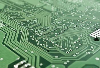Detailed view of a green circuit board with complex patterns and pathways. HD wallpaper