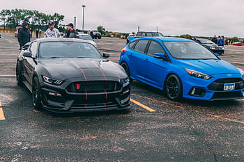 Black GT350 and blue Focus RS parked with spectators in the background. HD wallpaper
