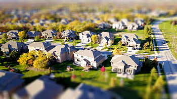 Tilt-shift aerial of a suburban neighborhood with green lawns and roads. HD wallpaper