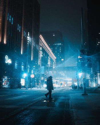 Silhouetted pedestrian crossing a snowy street in downtown Minneapolis at night. HD phone wallpaper