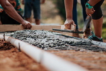 Construction workers leveling fresh cement on a sunny day at an outdoor site. HD wallpaper