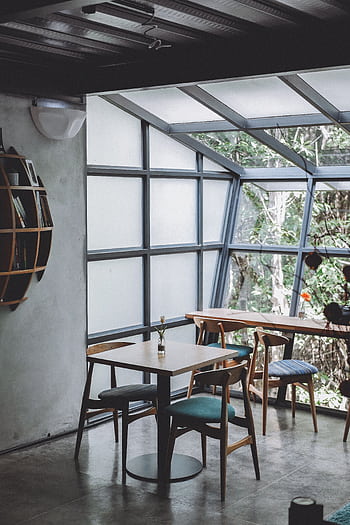 Inviting café interior with wooden furniture and large glass windows letting in natural light. HD phone wallpaper