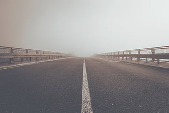 A misty road creating an atmospheric perspective and moody ambiance. HD wallpaper