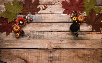 Warm autumn-themed table setting with coffee, leaves, and candles. HD wallpaper