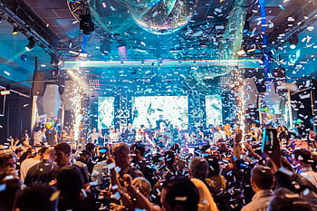 Vibrant nightclub scene in Mantua, Italy, featuring a lively crowd, confetti, and colorful lights. HD wallpaper