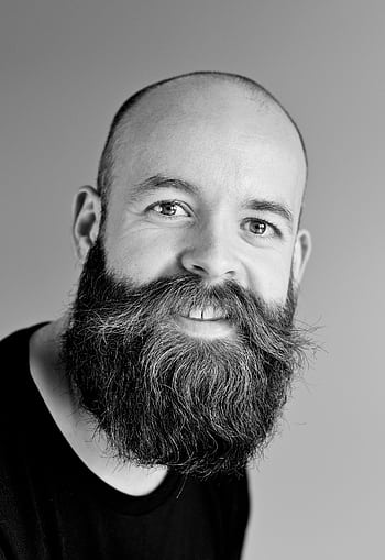 Black and white portrait of a smiling bald man with a large beard in a studio setting. HD phone wallpaper
