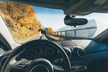 View from car interior driving through a scenic mountain road with autumn foliage and clear skies. HD wallpaper