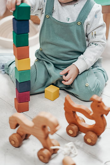 A child enjoying playtime indoors with colorful wooden blocks and toys. HD phone wallpaper