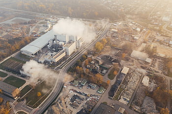 Aerial view showcasing an industrial complex in Poznań, Poland, emitting smoke and steam. HD wallpaper