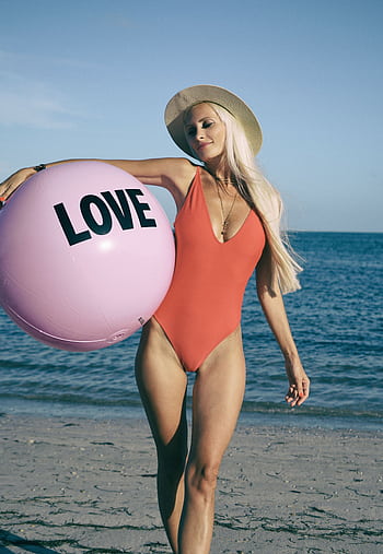 Young woman in swimsuit holding a pink love ball on Miami beach. HD phone wallpaper