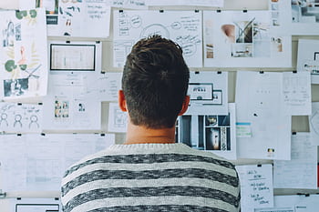 A man stands in front of a wall filled with creative ideas and plans. Ideal for innovation themes. HD wallpaper
