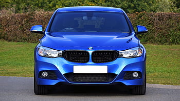 Front view of a stylish blue BMW sedan parked outdoors on a rural road. HD wallpaper