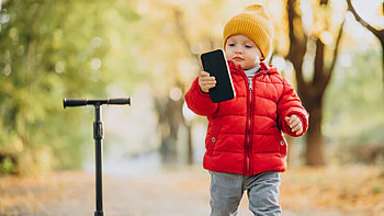 Cute Baby Boy Is Wearing Red Jerkin And Yellow Woolen Knitted Cap Holding Mobile Standing In Colorful Blur Bokeh Background Cute HD wallpaper