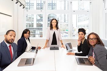 Professional team collaborating in a bright, modern conference room with laptops. HD wallpaper
