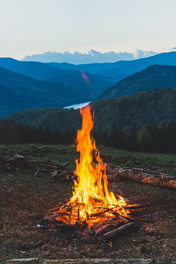A serene campfire with a stunning mountain backdrop in Romania's Lunca Vişagului. HD phone wallpaper