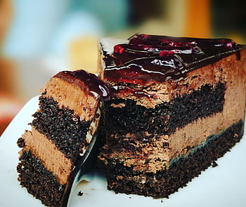 Close-up of a rich chocolate cake slice with blueberry topping, perfect for dessert lovers. HD wallpaper