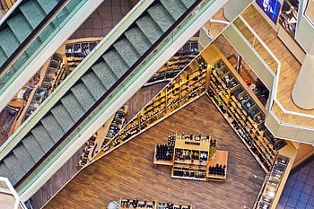 Aerial view of a stylish shopping mall showcasing escalators and well-organized retail displays. HD wallpaper