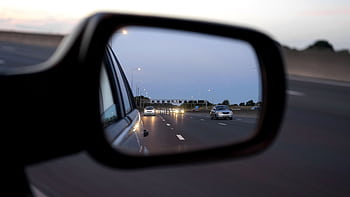 View of cars on the highway reflected in a vehicle's side mirror at twilight, capturing motion and speed. HD wallpaper