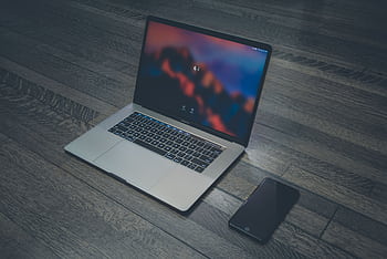 A sleek laptop and smart placed on wooden flooring, showcasing contemporary technology. HD wallpaper