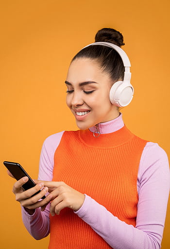 A woman in vibrant attire enjoying music on heads with a smart. HD phone wallpaper