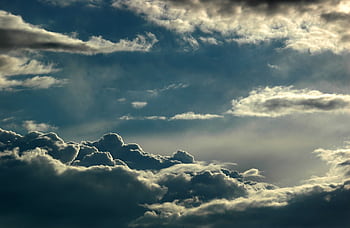 Dramatic cloudscape featuring layered clouds with sunlight breaking through, depicting a captivating sky scene. HD wallpaper