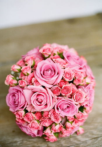 Beautiful circular arrangement of pink roses displayed on a rustic wooden surface. HD phone wallpaper