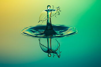A stunning macro graph capturing a water droplet splash with vibrant colors and reflection. HD wallpaper